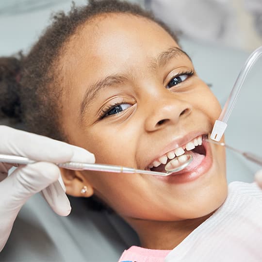 A young girl gets her teeth examined and cleaned by a dentist.