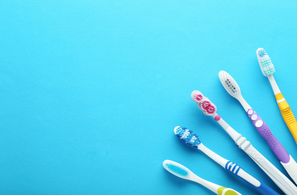 Five toothbrushes lined up in the corner of the image against a blue background