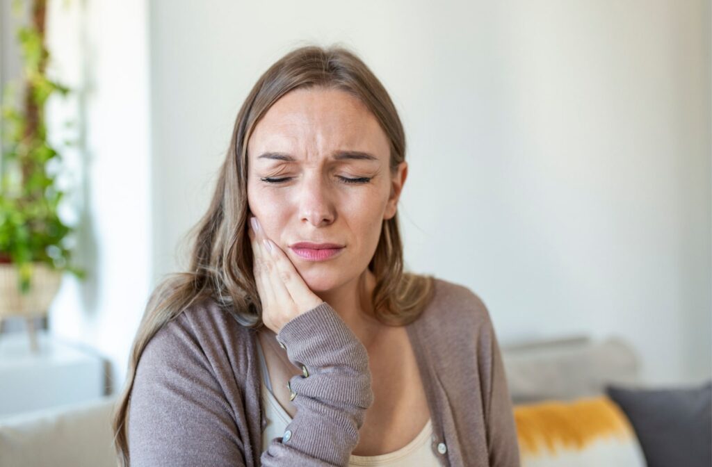 A woman holds her jaw from pain due to gum inflammation.