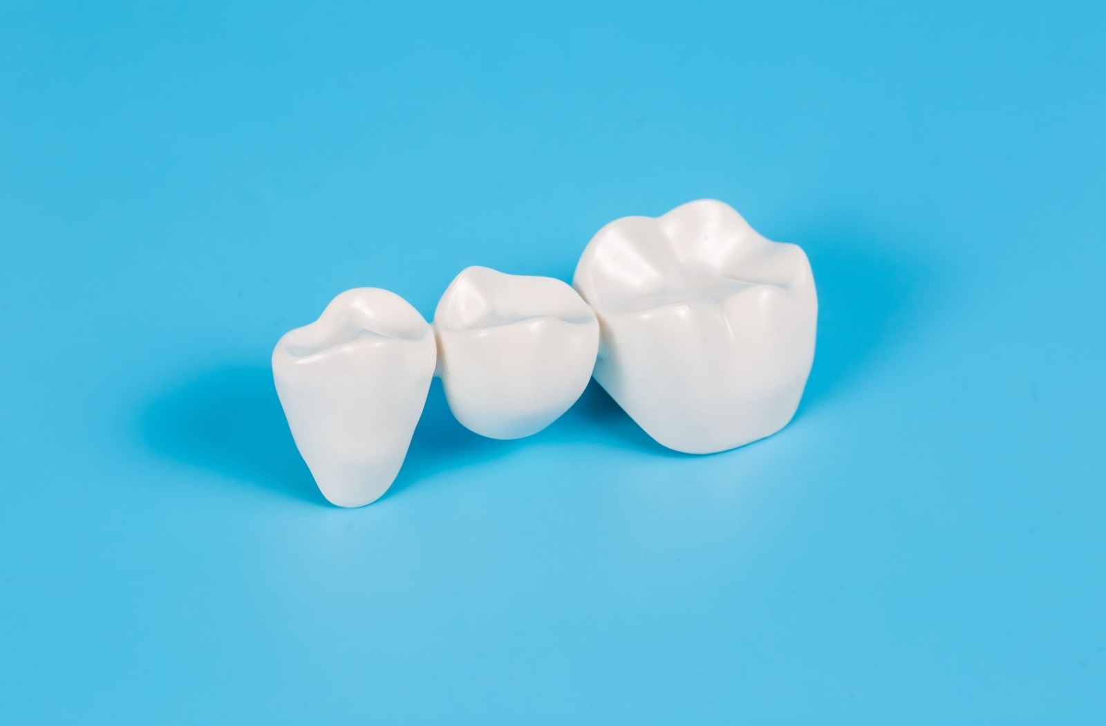 A close-up of a dental crown against a blue background.