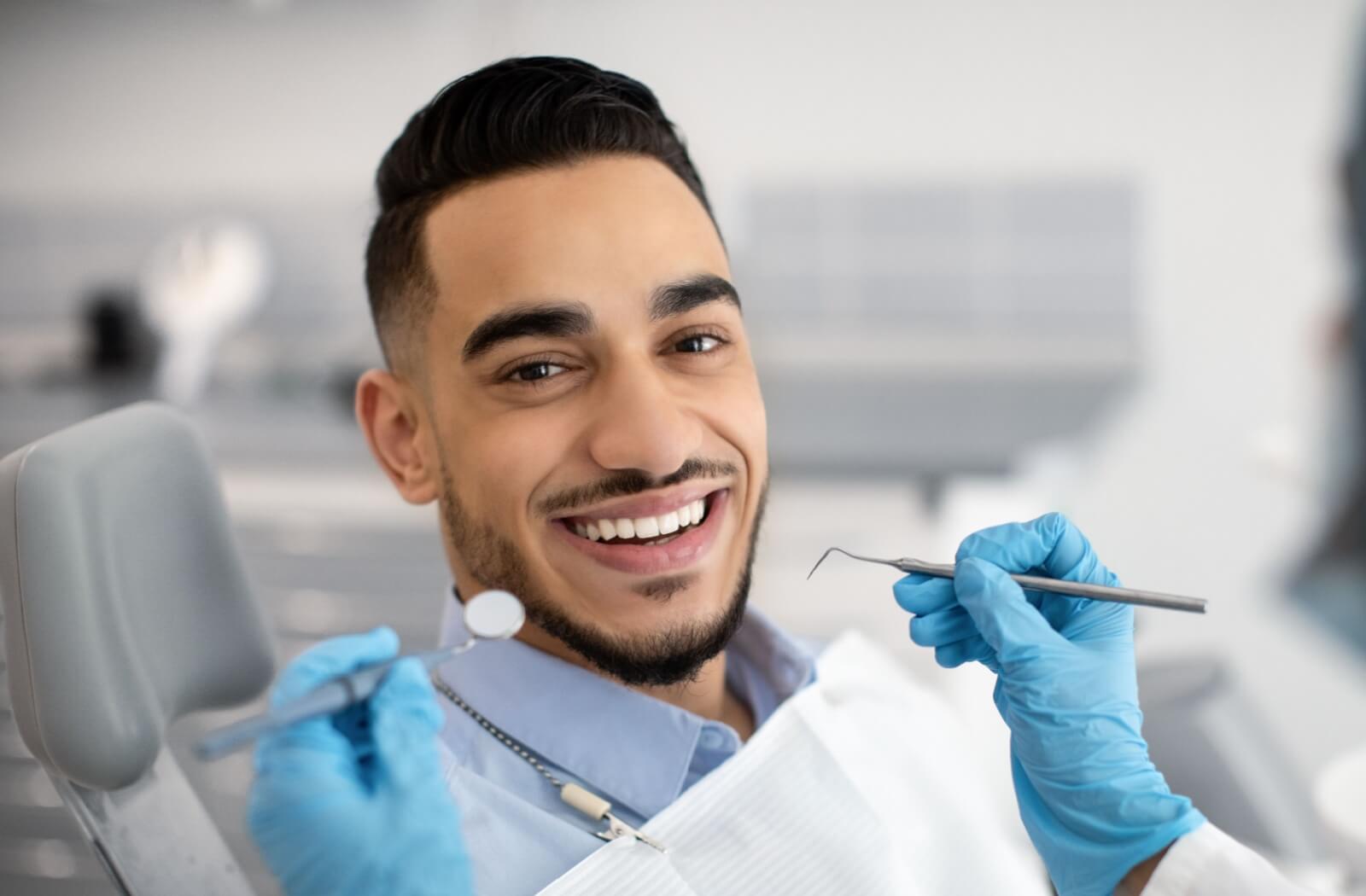 A happy man in a dentist's chair smiles before his cleaning