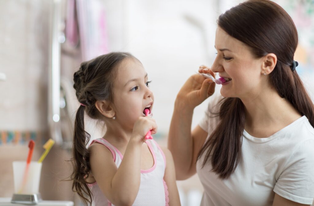 A woman and her daughter brush their teeth at home to be ready for their next dental exam