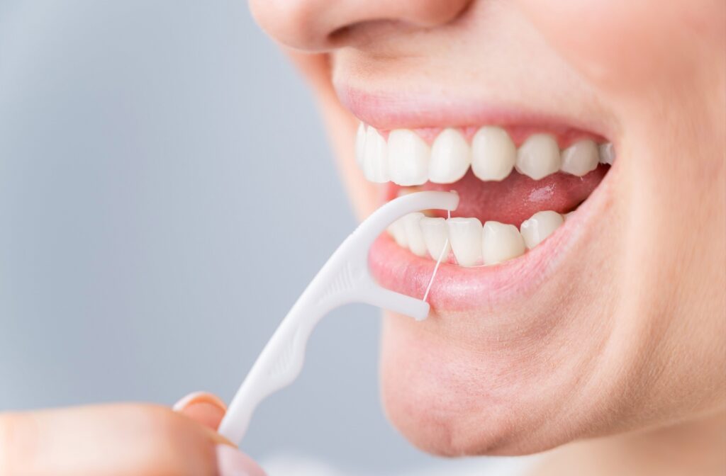 A patient using a dental pick as an alternative to flossing their teeth.