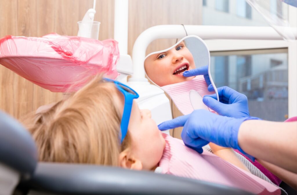  Using a mirror, a dentist shows their young patients' restored smile.