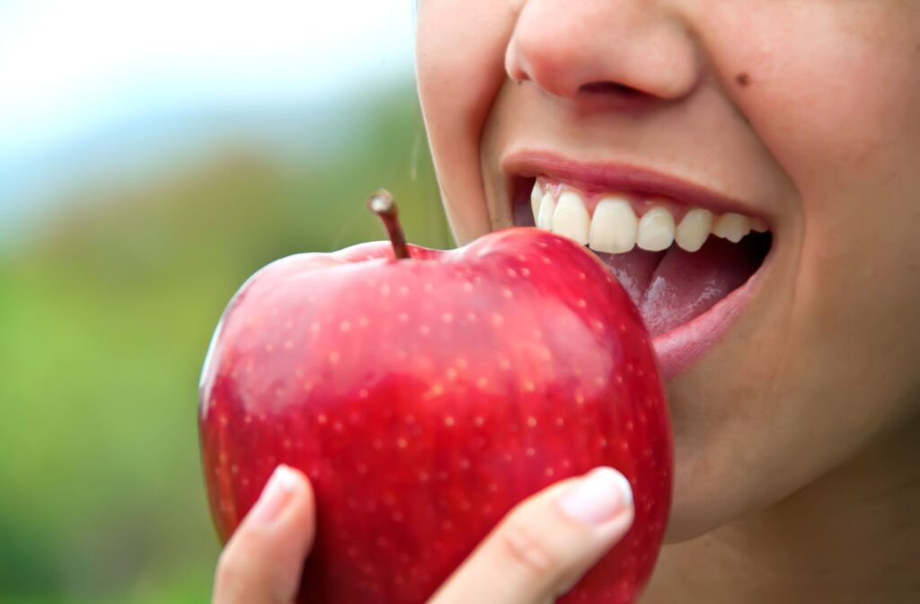 Close up of a person's mouth while they take a bite out of an apple
