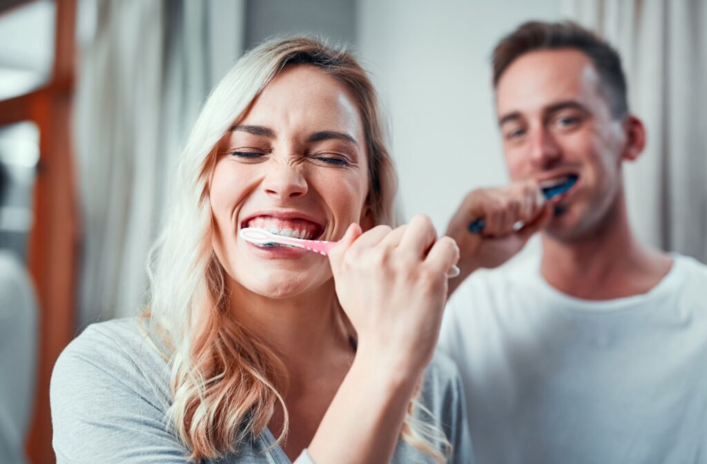 A husband and wife brushing their teeth together.