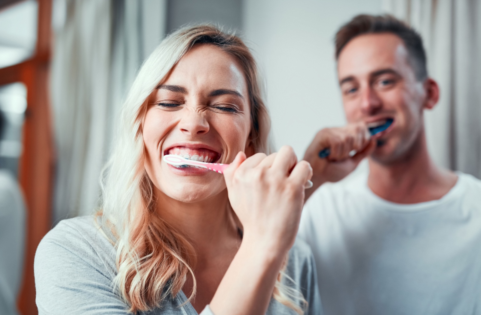 A husband and wife brushing their teeth together.